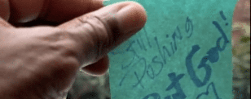 Hand holding note with motivational message.